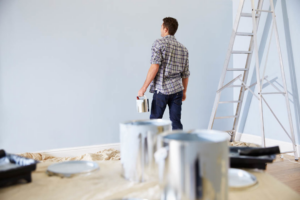 A person holding a paint can, admiring a freshly painted wall, representing painting services by World General Construction LLC in Everett, WA.
