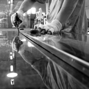 A person wearing gloves carefully working on a large piece of glass at Capitol City Glass & Screen Co. in Columbus, OH