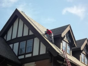 A person working on a steep residential roof with a ladder system at Superior Roof Support in Milano, TX.