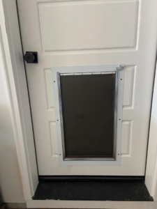 A newly installed pet door in a white interior door by Green River Utilities in Caldwell, ID.