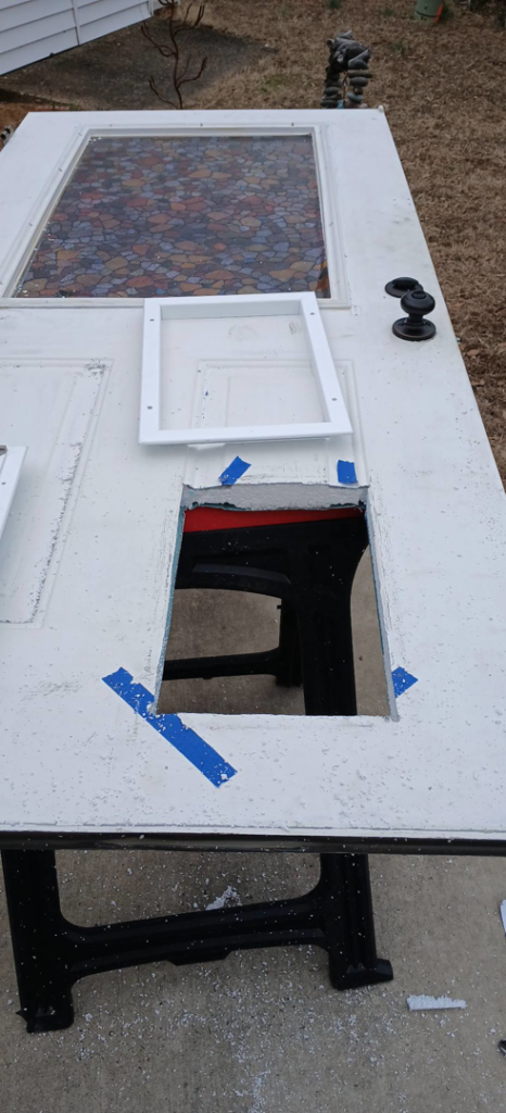 A residential door on sawhorses with a cutout for a pet door installation in progress by Heath Universal Renovations in North Little Rock, AR.