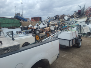 A pickup truck and trailer loaded with scrap metal and appliances at GJR Scrap Metals in Kansas City, MO.