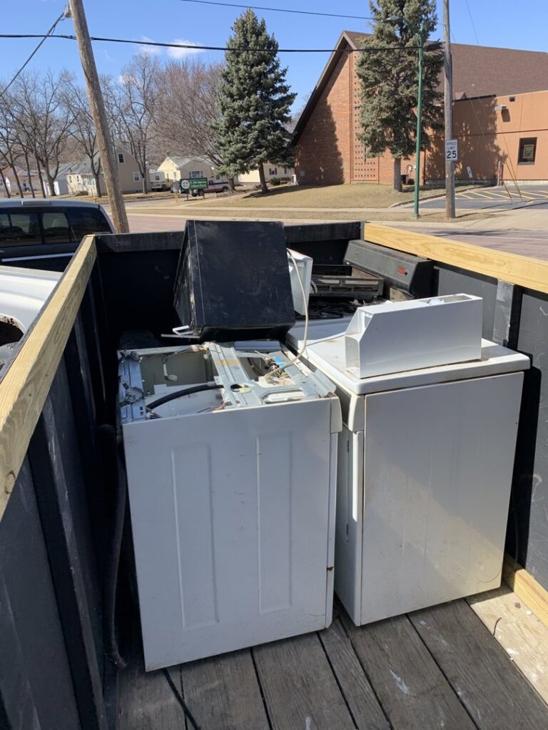 A pickup truck loaded with old washing machines and a television for removal by WeHaul Hauling & Junk Removal in Sioux Falls, SD.