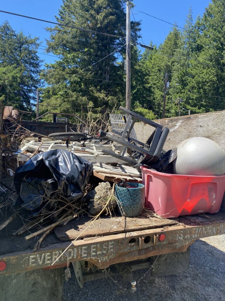 A pickup truck bed loaded with household junk, including branches, a plastic chair, and trash bags, for Down and Dirty Junk Removal in Tacoma, WA.