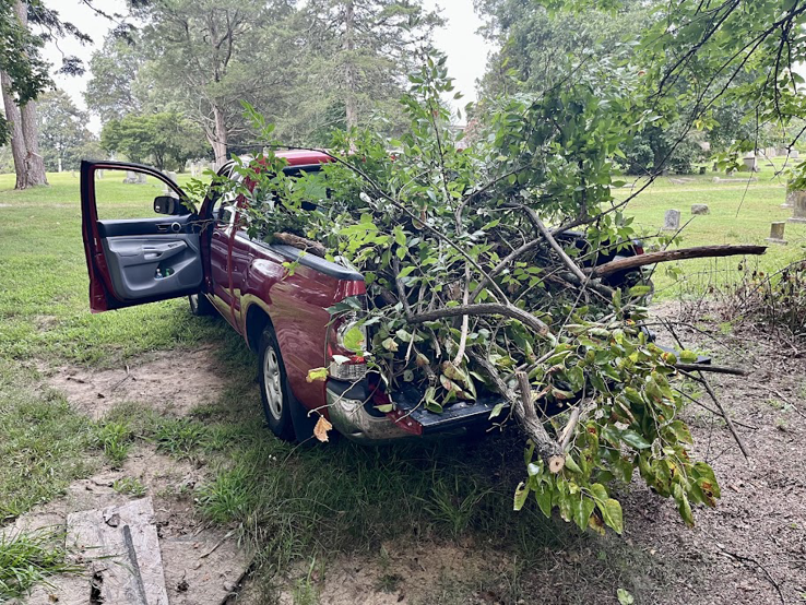 A red pickup truck loaded with tree branches and debris from a cemetery cleanup by Stone Cold Restorations in Durham, NC.