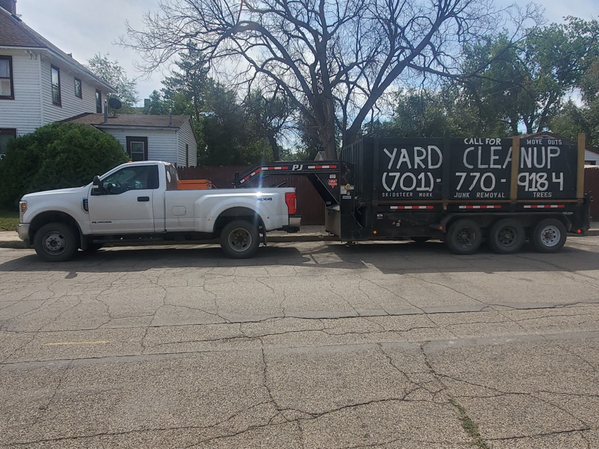 A white pickup truck hitched to a black dump trailer for junk removal services by 701 Scrap in Williston, ND.