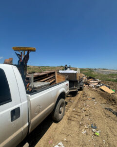 A Grawe Junk & Demo pickup truck with a dump trailer full of debris at a job site in Arlington, TX, ready for general junk removal.