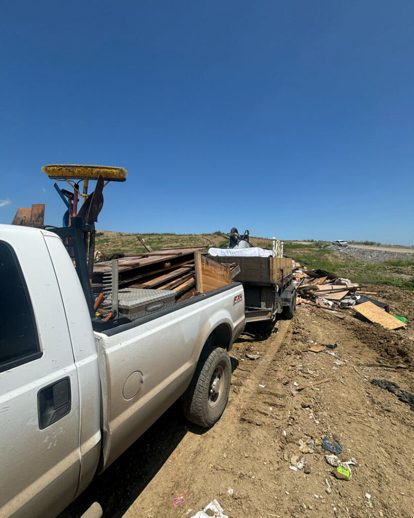 A Grawe Junk & Demo pickup truck with a dump trailer full of debris at a job site in Arlington, TX, ready for general junk removal.