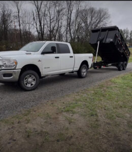 A white pickup truck with an attached black dump trailer, used for junk removal by The Removal Squad LLC in Orlando, FL.
