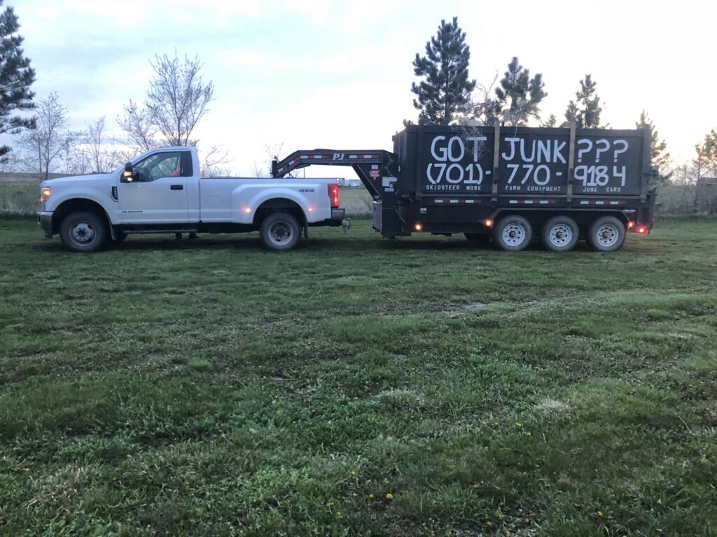A pickup truck with a dump trailer featuring "GOT JUNK???" text, ready for junk removal by 701 Scrap in Williston, ND.
