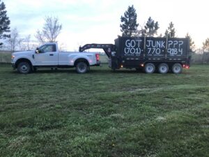 A pickup truck with a dump trailer featuring "GOT JUNK???" text, ready for junk removal by 701 Scrap in Williston, ND.