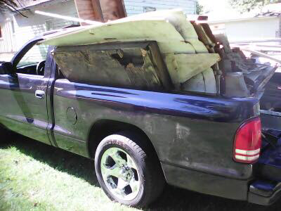 A pickup truck with its bed full of various junk and construction debris, ready for removal by D&D Hauling in Des Moines, IA.