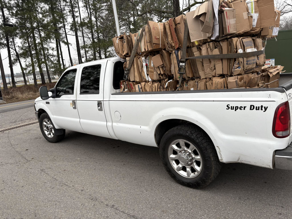 A white pickup truck hauling a large stack of baled cardboard for E&k logistics an Recycling LLC in Hoover, AL.