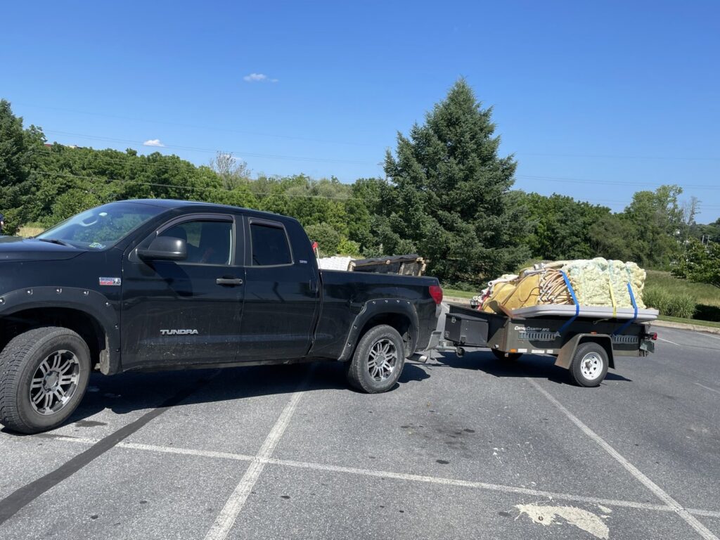 A pickup truck hauling a trailer loaded with a dismantled hot tub, a junk removal service by Nu Earth Hauling and Recycling in Allentown, PA.