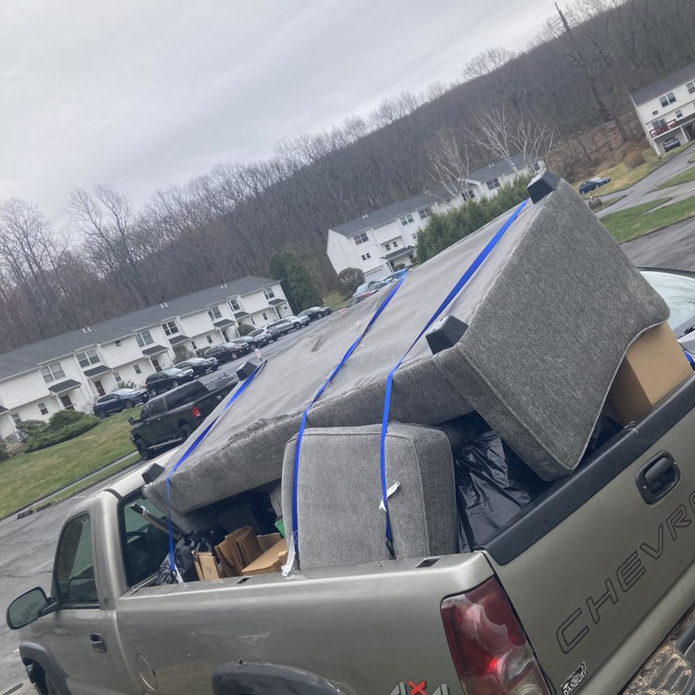 A pickup truck loaded with a sofa and other junk for removal by Happy Hauling & Junk Removal in Hartford, CT.