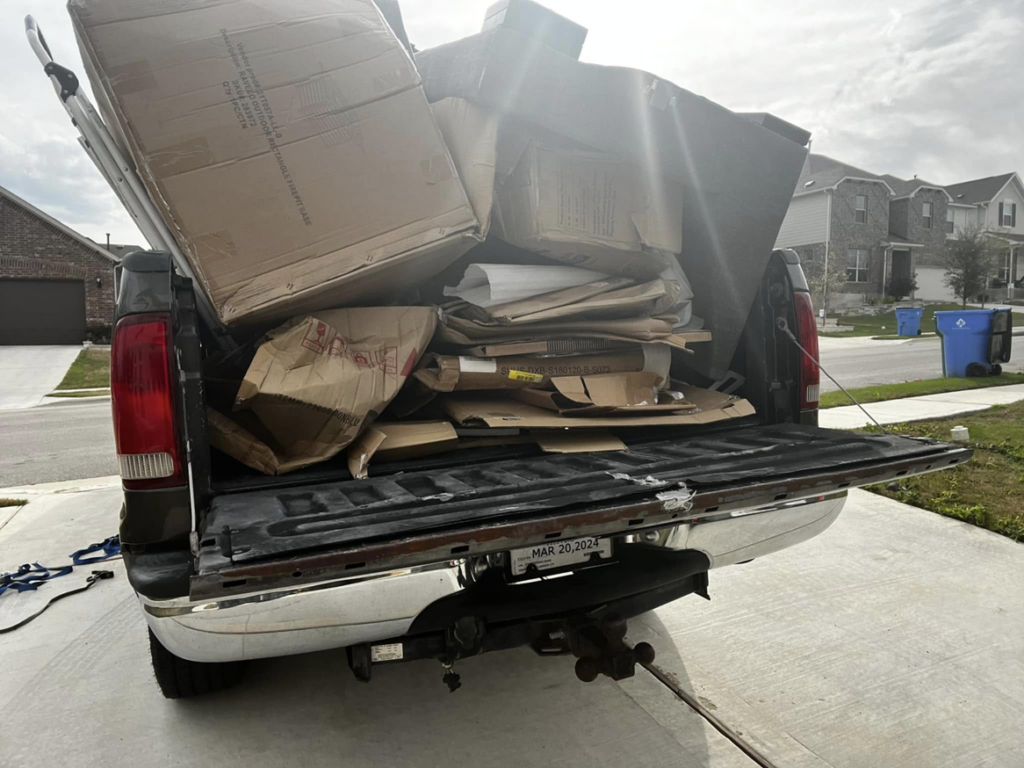 A pickup truck loaded with numerous cardboard boxes and construction debris for removal by ONLY Junk Removal Services in Austin, TX.
