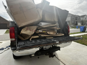 A pickup truck loaded with numerous cardboard boxes and construction debris for removal by ONLY Junk Removal Services in Austin, TX.