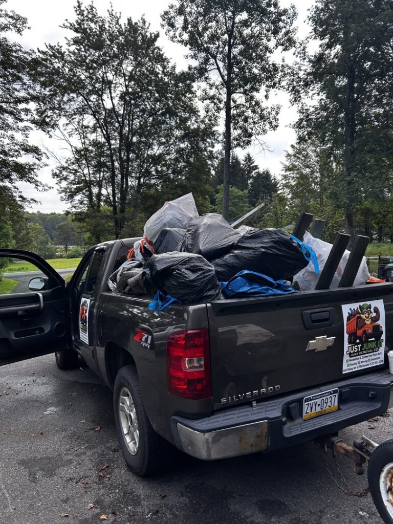 A Just Junk It pickup truck loaded with bags of trash and various junk items for removal in Lancaster, PA.