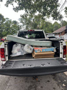 A pickup truck loaded with a mattress, trash bags, and cardboard boxes for removal by ONLY Junk Removal Services in Austin, TX.