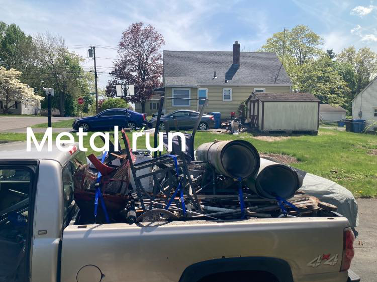 A pickup truck loaded with various metal junk items for removal by Happy Hauling & Junk Removal in Hartford, CT.
