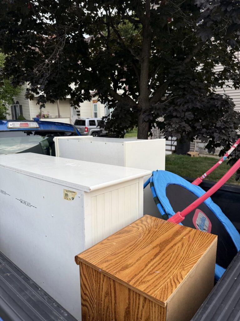 A pickup truck loaded with furniture pieces and a trampoline, ready for junk removal by Clutter Bandit in Albany, NY.