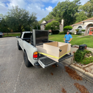 A Litter Hitters pickup truck loaded with a television and cabinet for junk removal from a residential home in Jacksonville, FL.