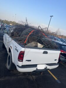 A white pickup truck loaded with a large pile of branches and yard waste for Load and Go Junk Removal in Ames, IA.