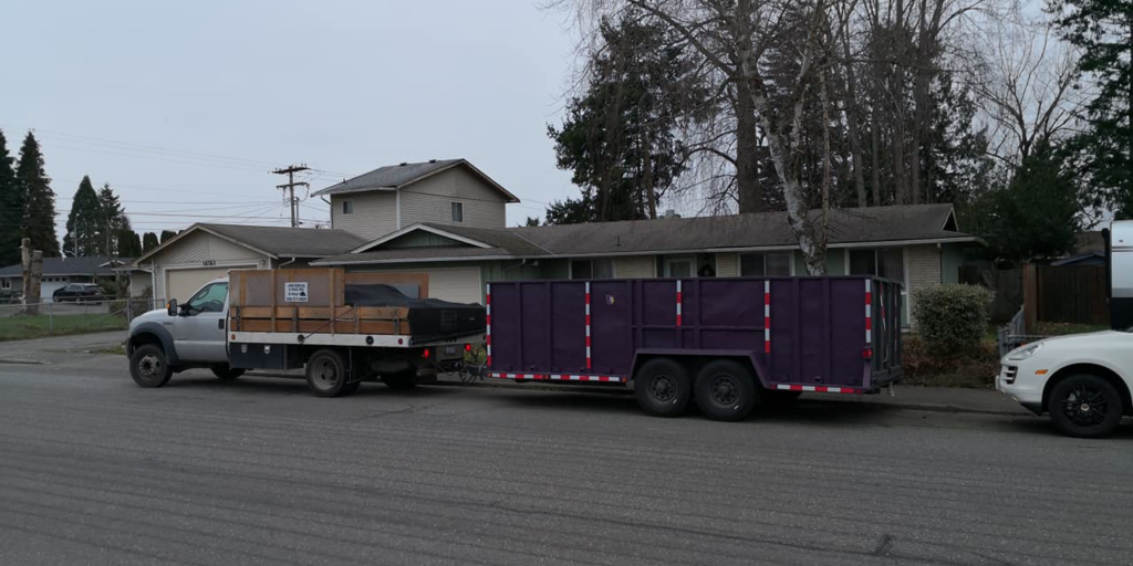 A pickup truck towing a purple dump trailer on a residential street, ready for hauling services by Gorilla Hauling in Kent, WA.