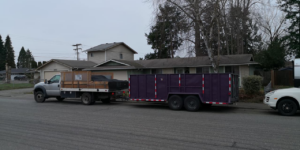 A pickup truck towing a purple dump trailer on a residential street, ready for hauling services by Gorilla Hauling in Kent, WA.