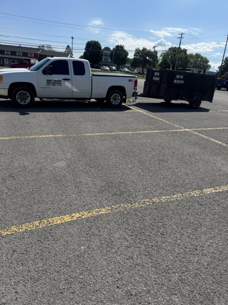 A Greybeard Dumpster Rentals pickup truck towing a branded dumpster trailer in a parking lot in Morgantown, WV.