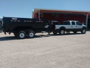 A pickup truck towing an empty dump trailer, used for junk removal services by Construction Removal Services Inc. in El Paso, TX.