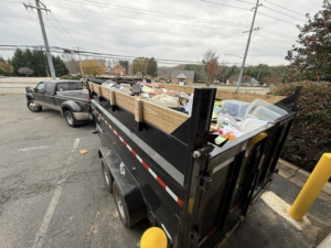 A pickup truck towing a full junk removal trailer, showcasing services by Freedom Hauling in California, MD.