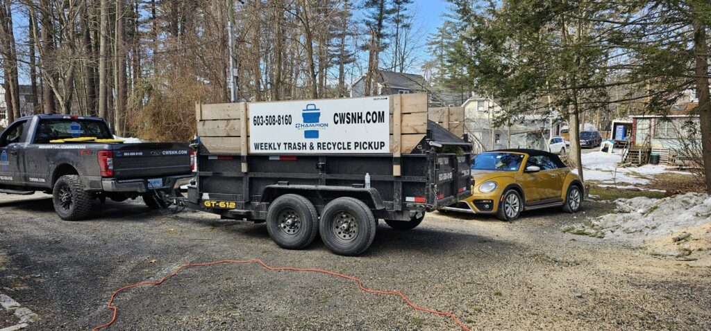 A Champion Waste Services pickup truck towing a large junk removal trailer in Londonderry, NH.