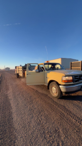 A pickup truck with a trailer loaded with junk on a dirt road, ready for removal by Quality Rent & Removal in Minot, ND.