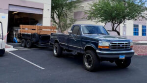 A blue pickup truck with a utility trailer, used for hauling and junk removal services by MLG Strong Hauling & Junk Removal LLC in Henderson, NV.