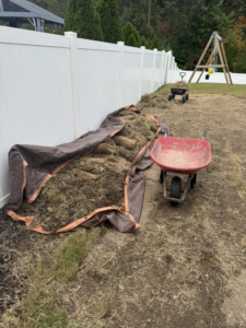 A pile of dried grass and sod covered by a tarp, ready for yard waste removal by JR's Rapid Junk Removal in Cary, NC