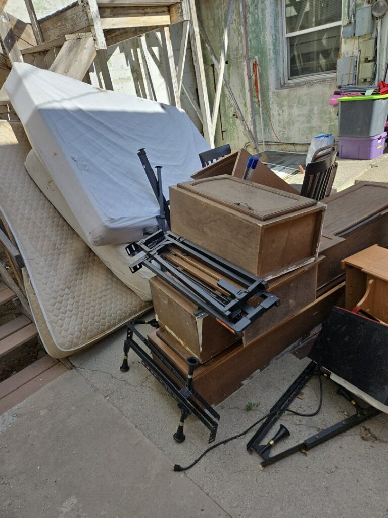 A large pile of mattresses, wooden furniture, and metal frames stacked outdoors for removal by Rubble Removers LLC in Riverton, WY.