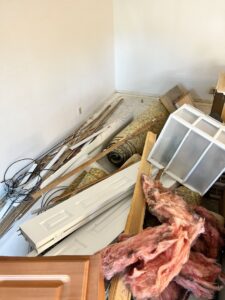 A large pile of mixed renovation debris, including doors, insulation, and wood, in a room for junk removal by Pack N Haul in West Valley City, UT.