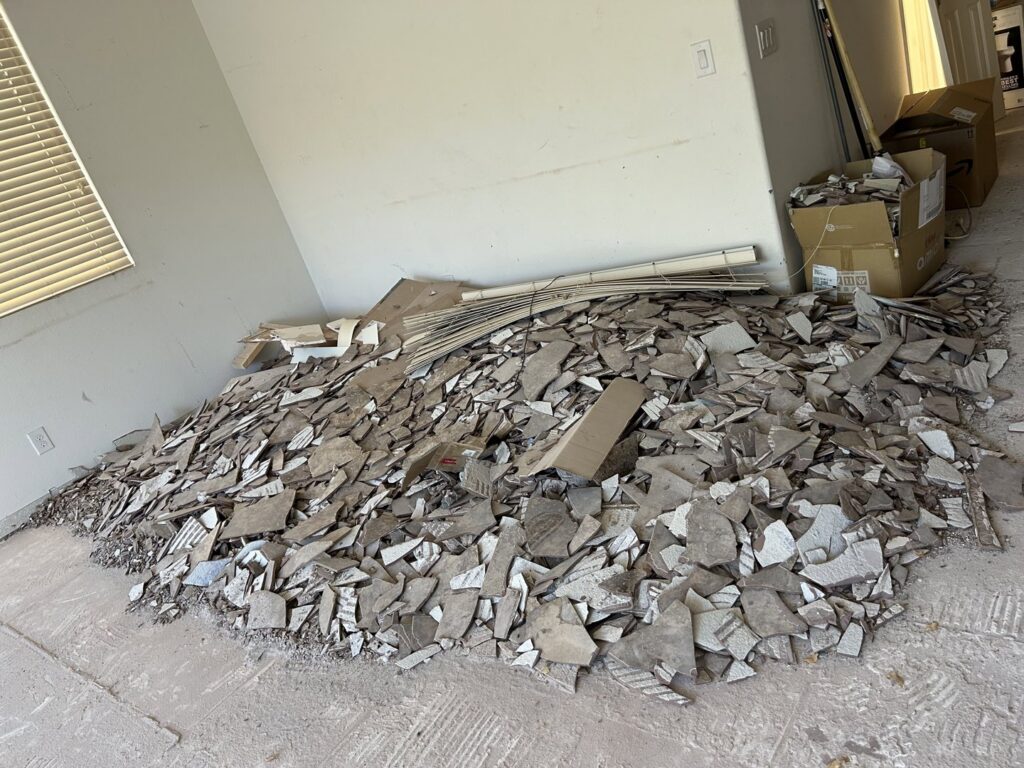 A large pile of broken tiles and construction debris on the floor, ready for removal by Tidy Toss Las Vegas, NV.