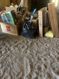 A pile of cardboard boxes, a black trash bag, and other debris on a gravel floor, ready for removal by Roadrunner JunkSmart Solutions LLC in Las Cruces, NM.