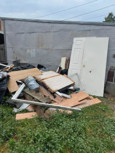 A large pile of construction debris, old doors, and general junk in a backyard, ready for removal by Bee There Junk Removal in Philadelphia, PA.