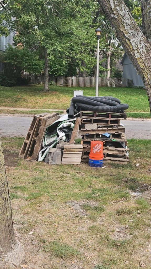 A large pile of construction debris, including pallets, pipes, and concrete blocks, ready for removal by Young Bucks Junk in Shawnee, KS.