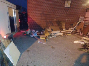 Construction debris and junk piled next to a trailer for C&C Dumpster Services in Omaha, NE.