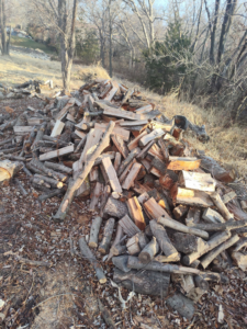 A large pile of cut firewood from tree removal services by Hoffman Construction Services, LLC in Saint Joseph, MO.