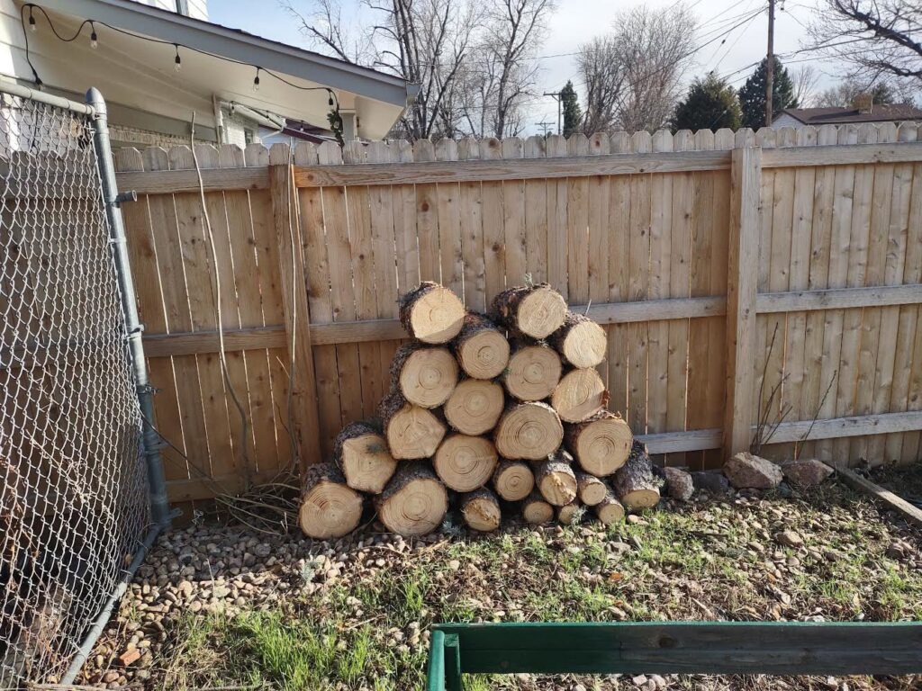 A pile of freshly cut logs, likely for firewood, from tree removal by DelaRosa Tree Service LLC in Denver, CO.