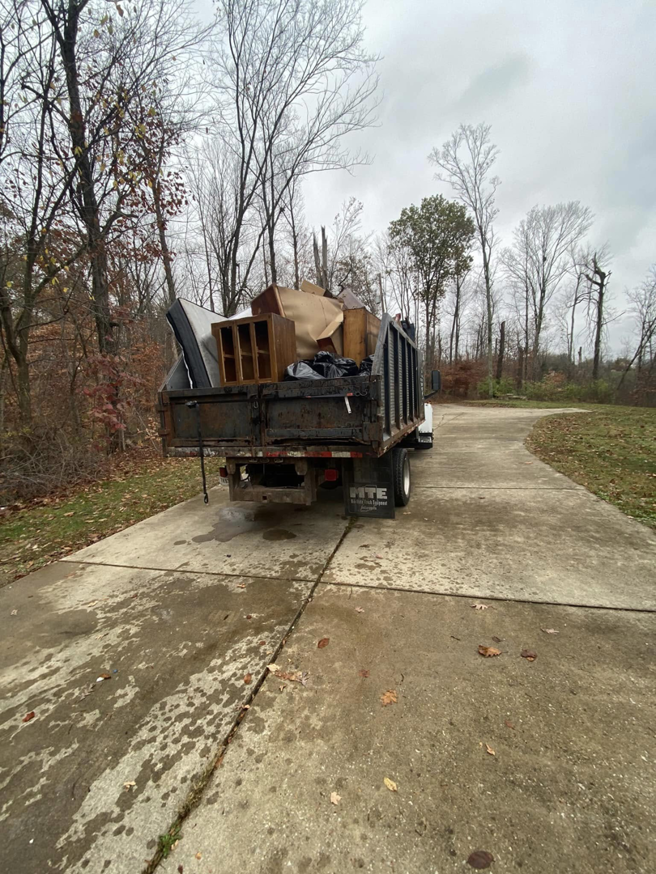 A large pile of old furniture and trash bags on a driveway, ready for junk removal by Hoosier Outdoor Services in Bloomington, IN.