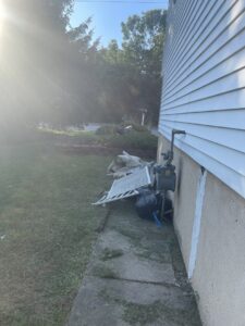 A pile of household junk and debris next to a house, ready for pickup by CK Junk Removal in New Bedford, MA