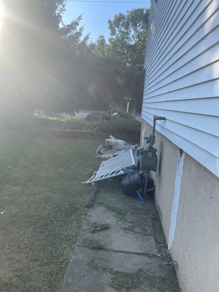 A pile of household junk and debris next to a house, ready for pickup by CK Junk Removal in New Bedford, MA