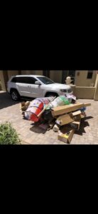 A large pile of household junk, including boxes, bags, and a play tunnel, on a driveway for removal by The Junkporter Junk Removal in Las Vegas, NV.
