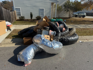 A large pile of old HVAC ductwork and cardboard boxes on a driveway for removal by Junkslingers NC in Cary, NC.